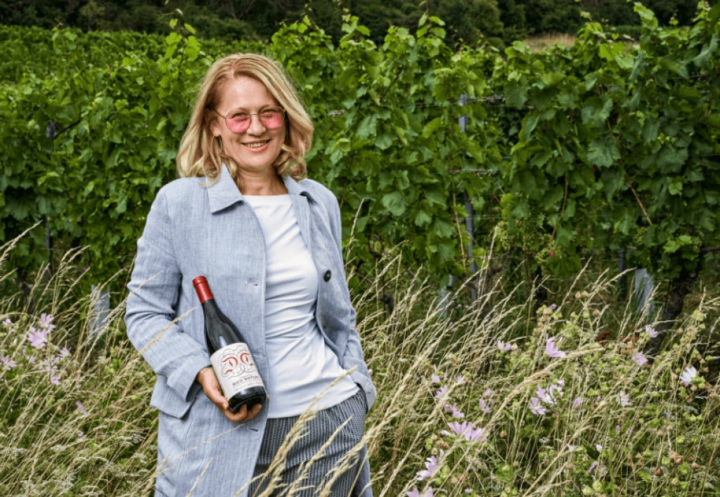 Winzerin Dorli Muhr hält eine Weinflasche im Weingarten