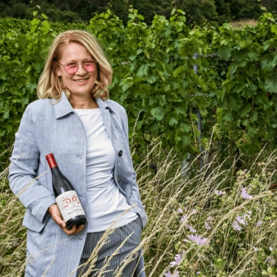 Winzerin Dorli Muhr hält eine Weinflasche im Weingarten